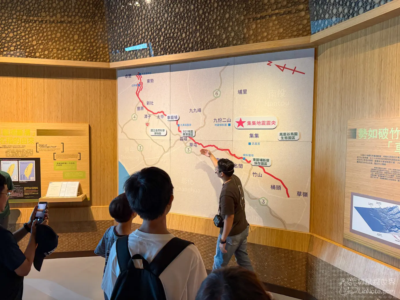 展覽館內導覽員舉手向遊客解說地震斷層分布圖