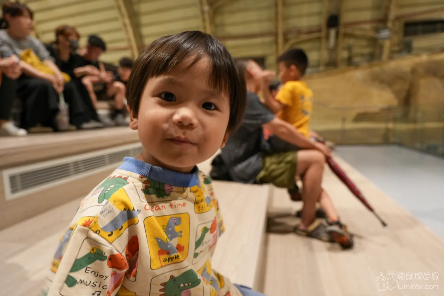 幼童坐在看台木質階梯上露出的開朗笑容