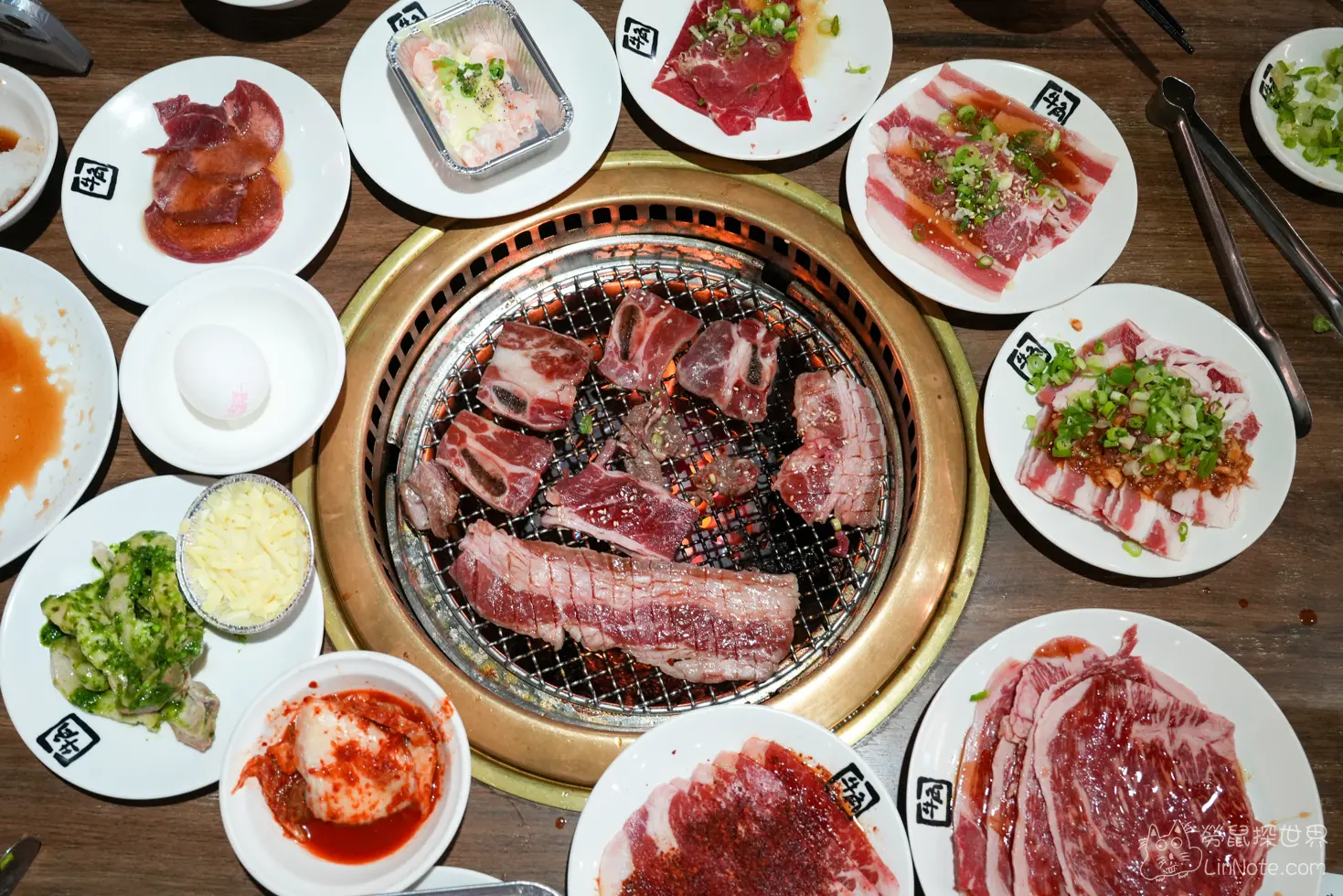 烤網上正燒烤著牛小排周圍擺滿各式生肉小碟