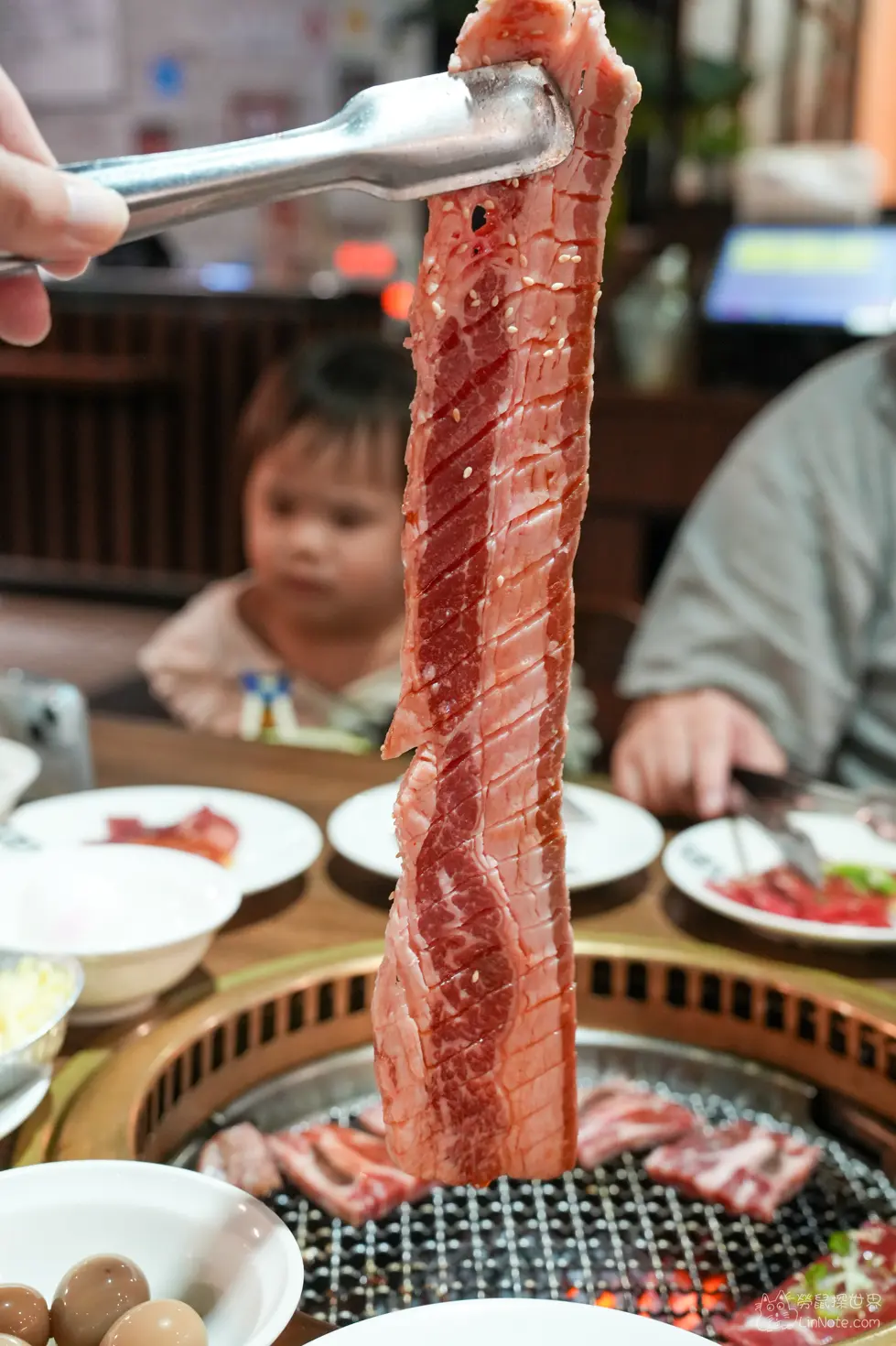 用夾子夾起切花處理的牛肉片懸掛於烤網上方