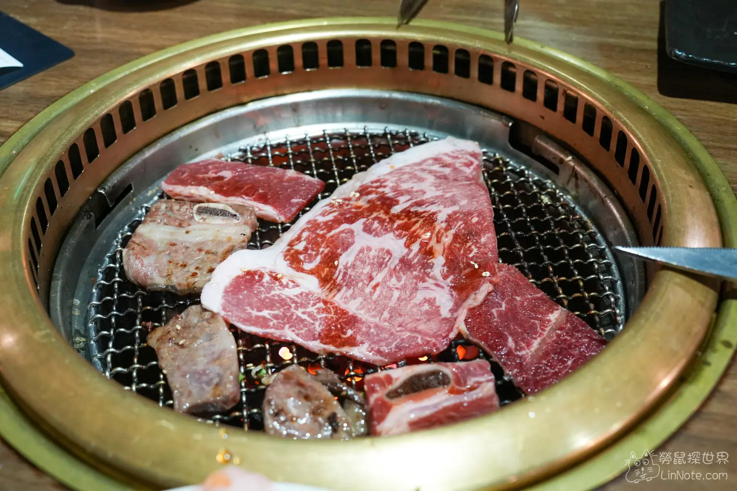 金屬烤爐中正以炭火燒烤著大片粉紅色生牛肉