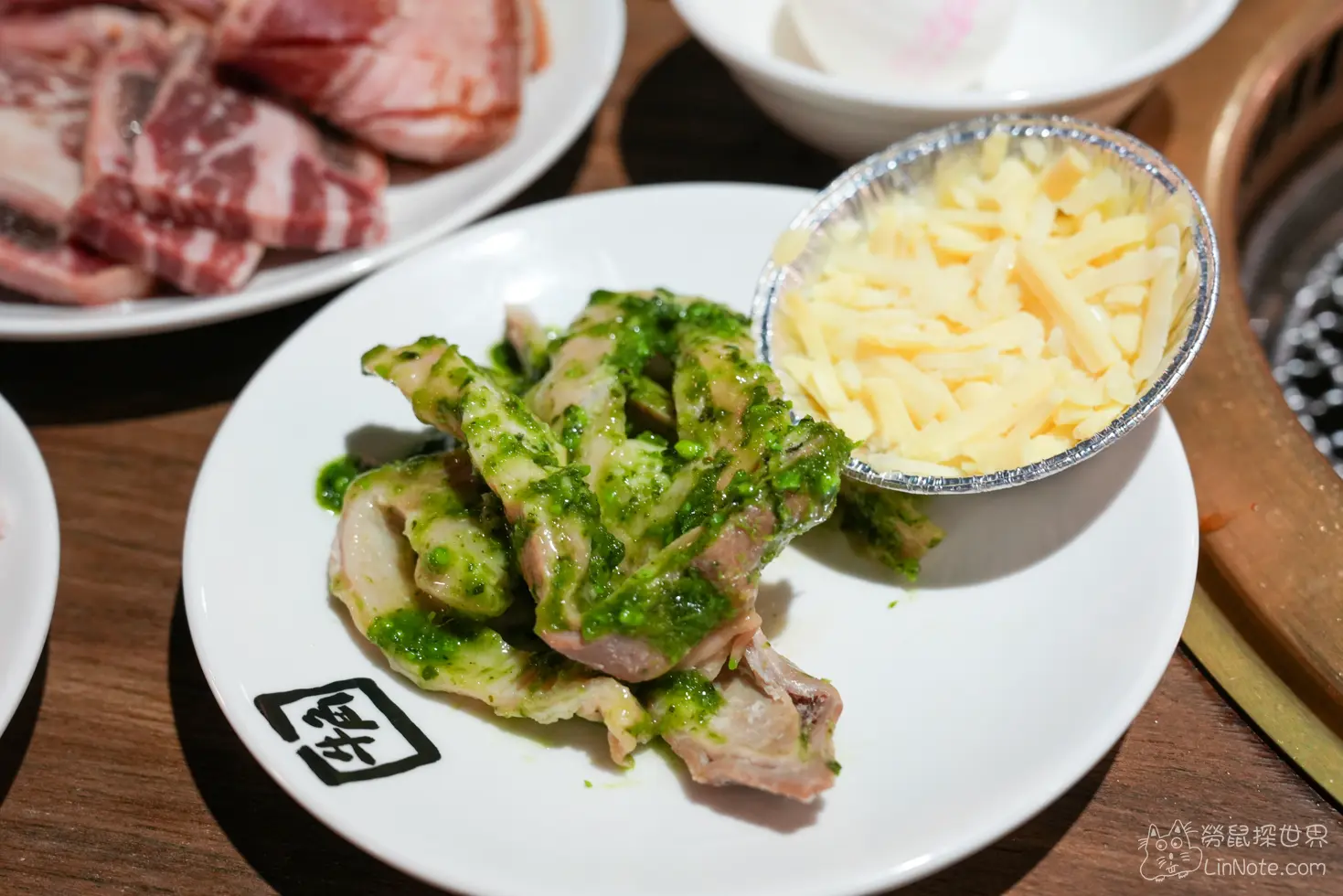 圓盤上的青醬醃製肉品旁附有裝滿乳酪絲的鋁箔碗