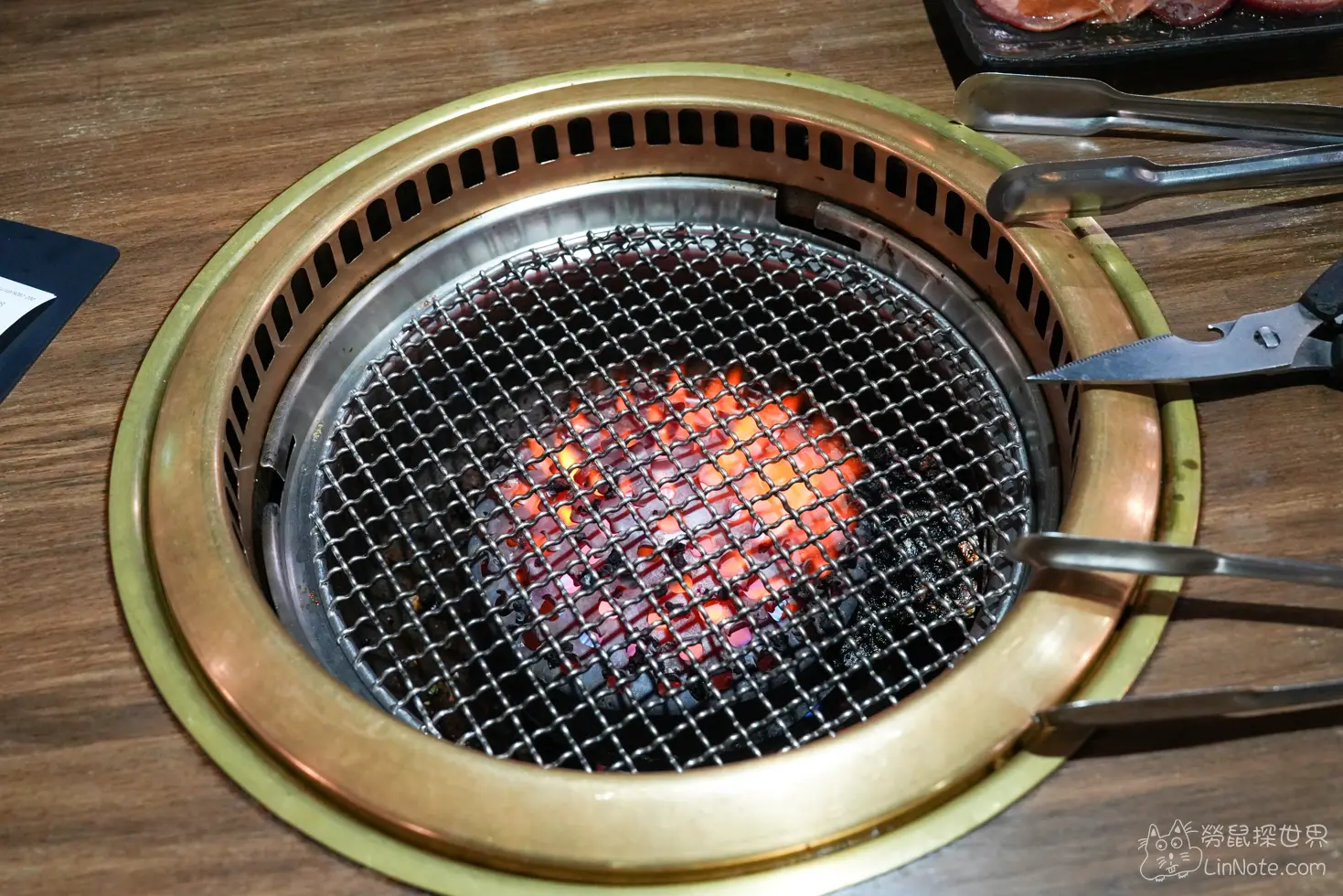 嵌入木質餐桌的金屬燒烤爐透出燒紅的炭火