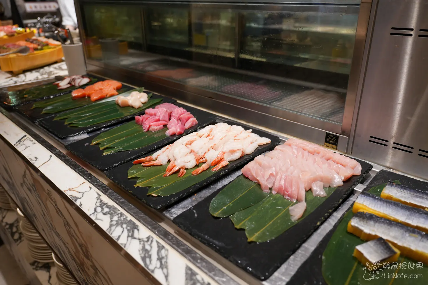 鮨影日料區黑色石板陳列的生魚片甜蝦與干貝生鮮