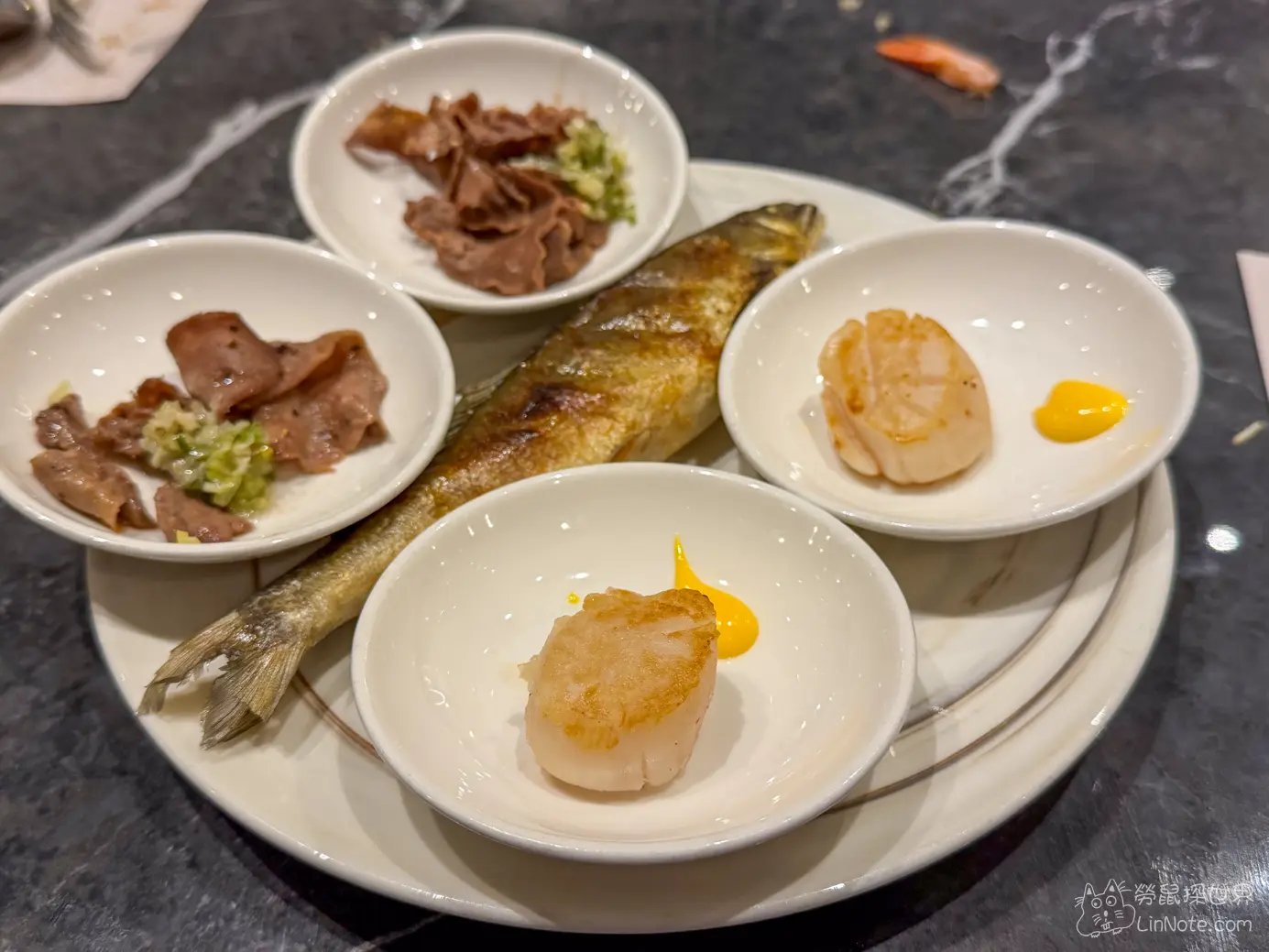 白色大圓盤盛裝的烤魚煎干貝與薄切肉片小碟