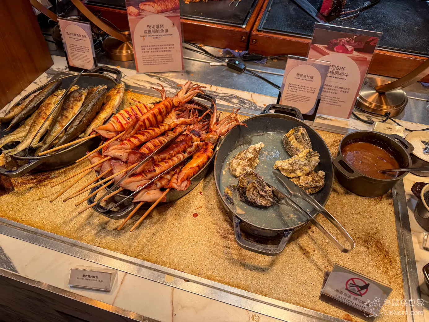 熟食海鮮檯上陳列的烤魚串烤魷魚與烤生蠔鐵鍋