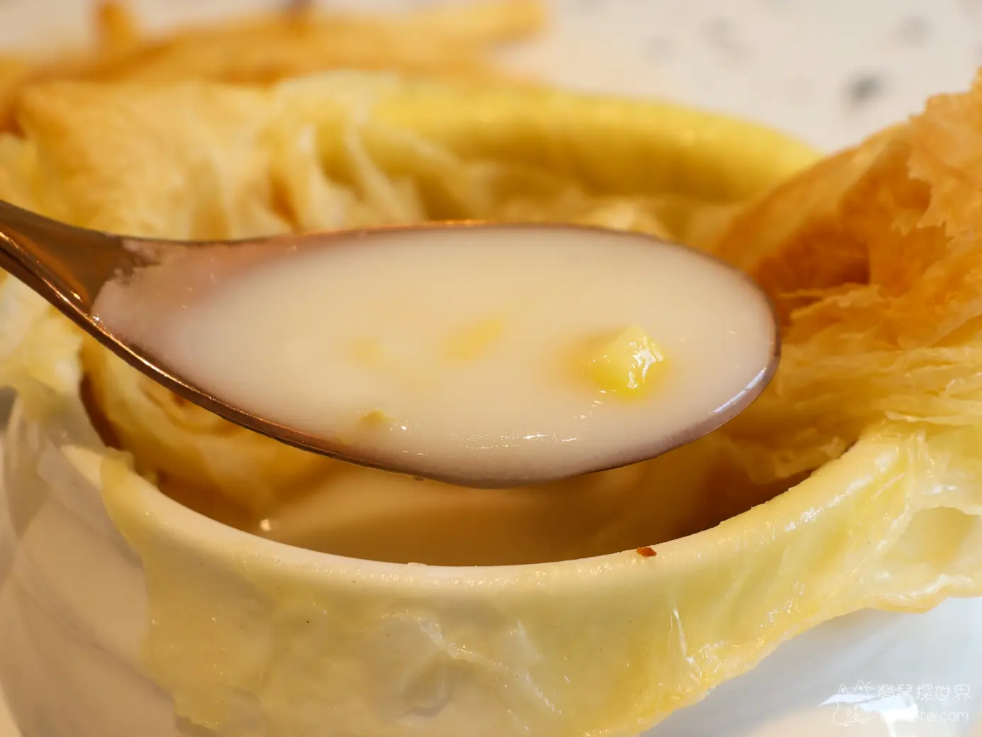 金屬湯匙舀起濃稠滑順的白色酥皮濃湯
