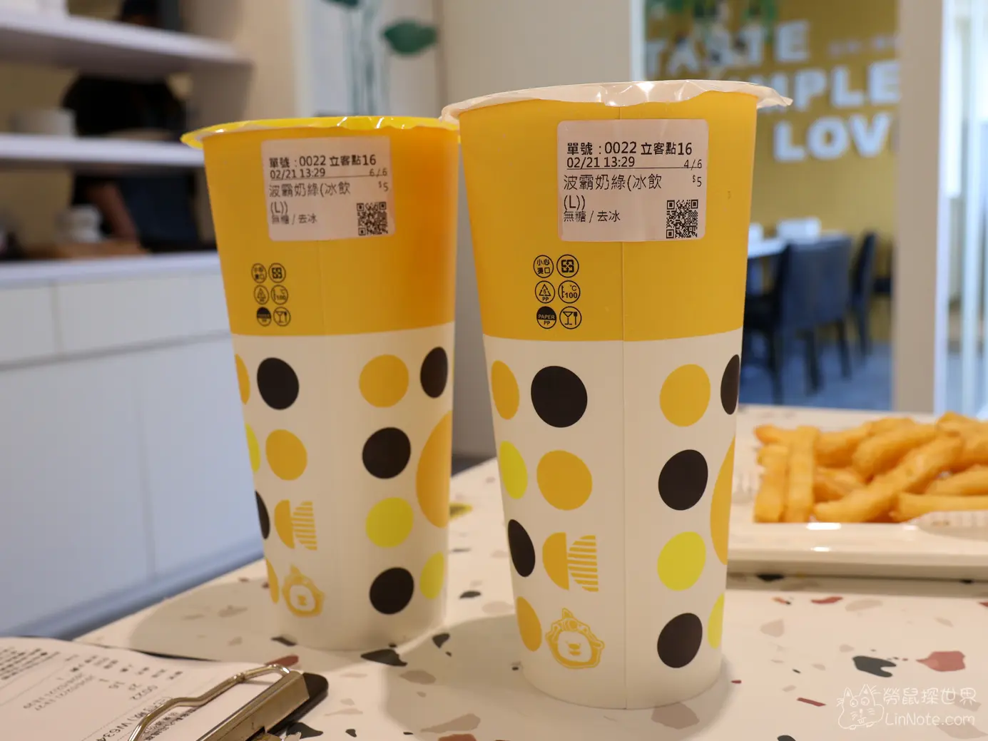 桌上並排擺放兩杯黃白圓點外帶紙杯的波霸奶綠