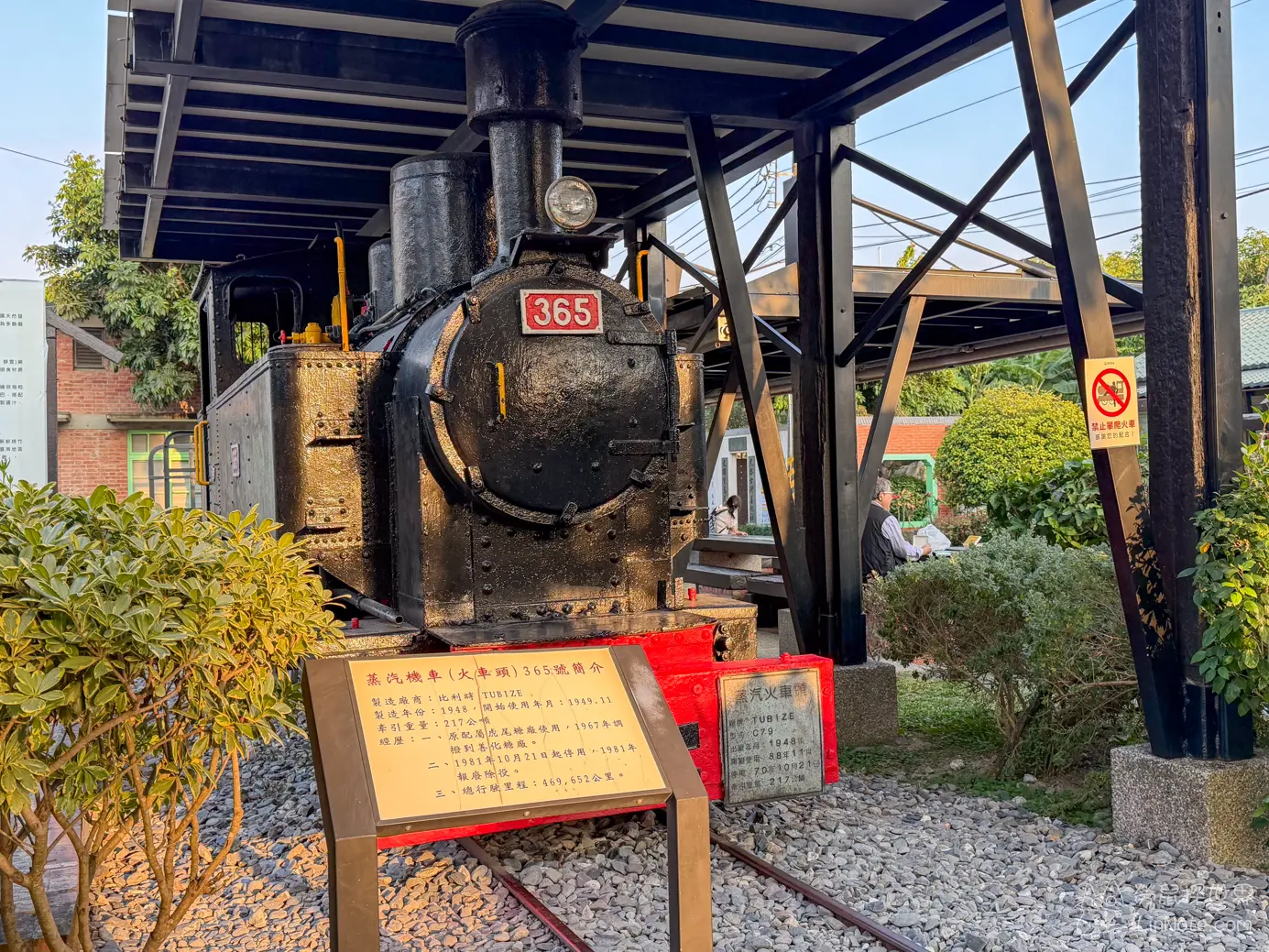 停放在棚架下的黑色365號老式蒸汽機車與解說牌