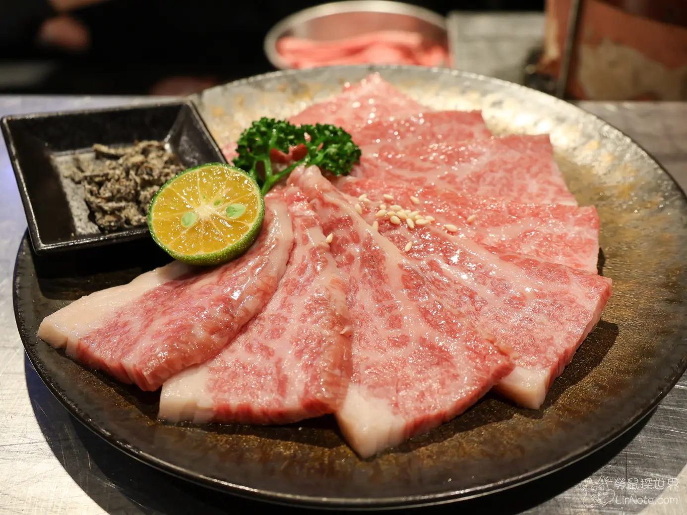 黑色圓盤中油花均勻細緻的日本和牛沙朗上蓋生肉切片