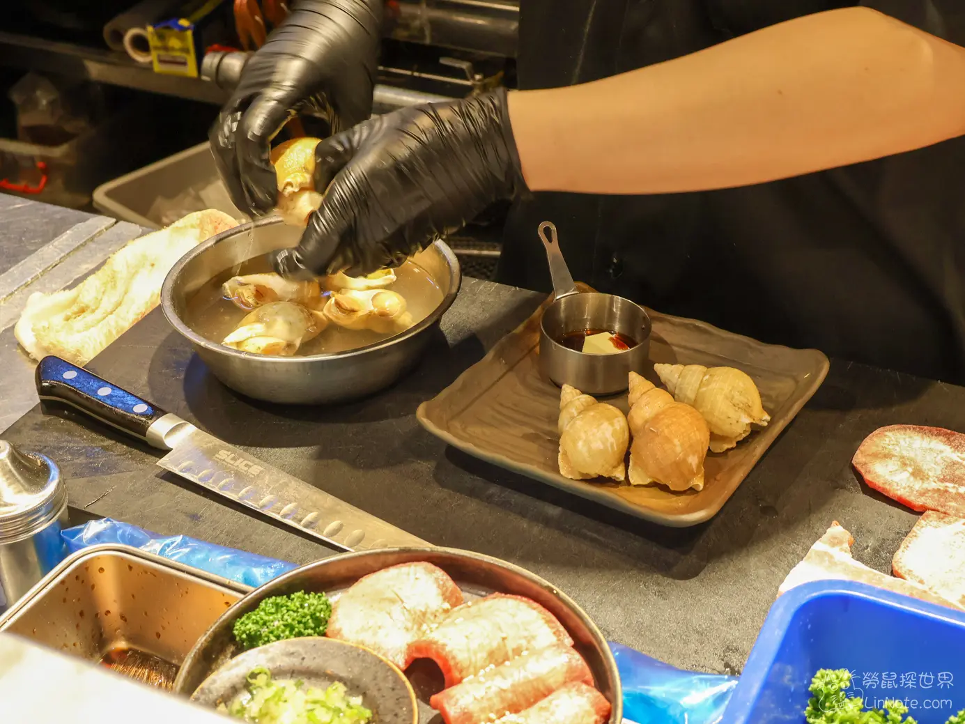 料理台前廚師戴著黑手套專注處理新鮮海螺海鮮食材