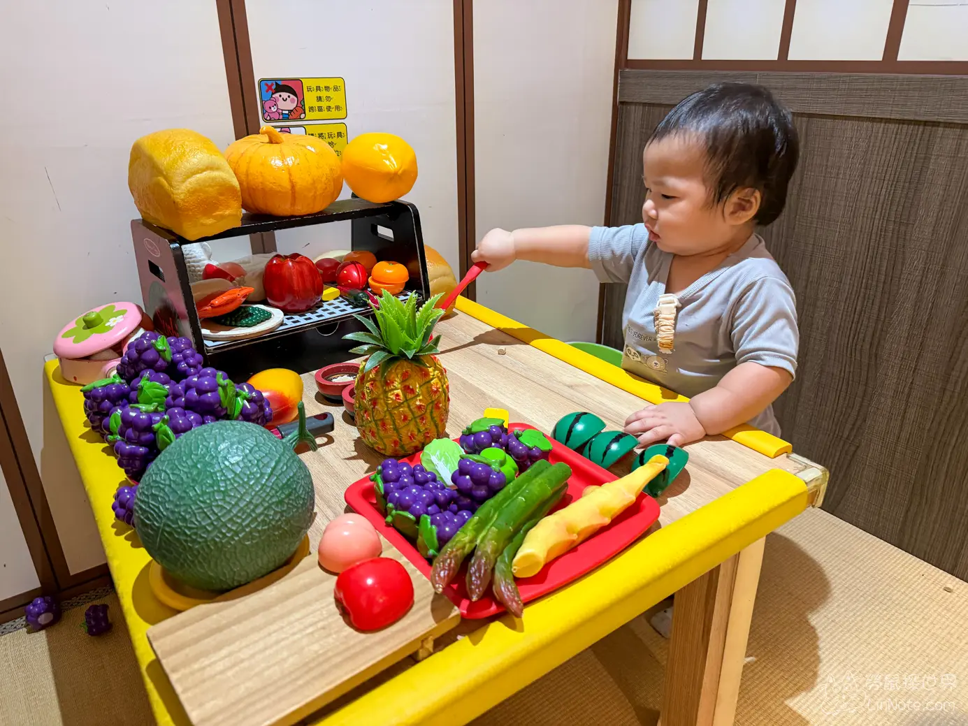 幼童拿著玩具小刀在桌前切擬真水果模型