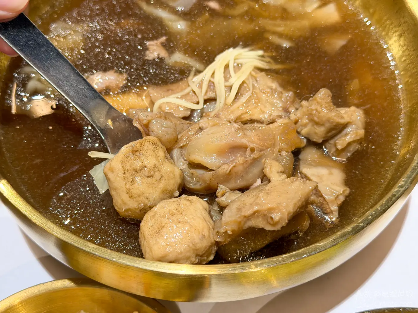 金色金屬碗中熱騰騰的湯與肉塊丸子配料