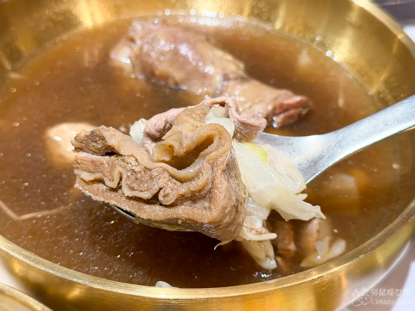 湯匙舀起湯內的羊肉片與燉煮高麗菜