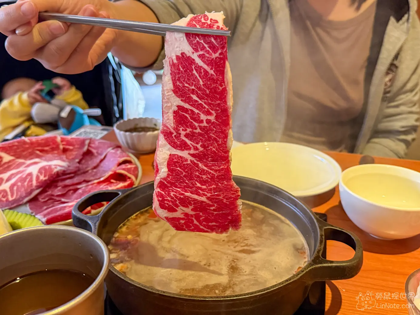 用筷子夾起牛魔王油花均勻的和牛肉片準備涮煮