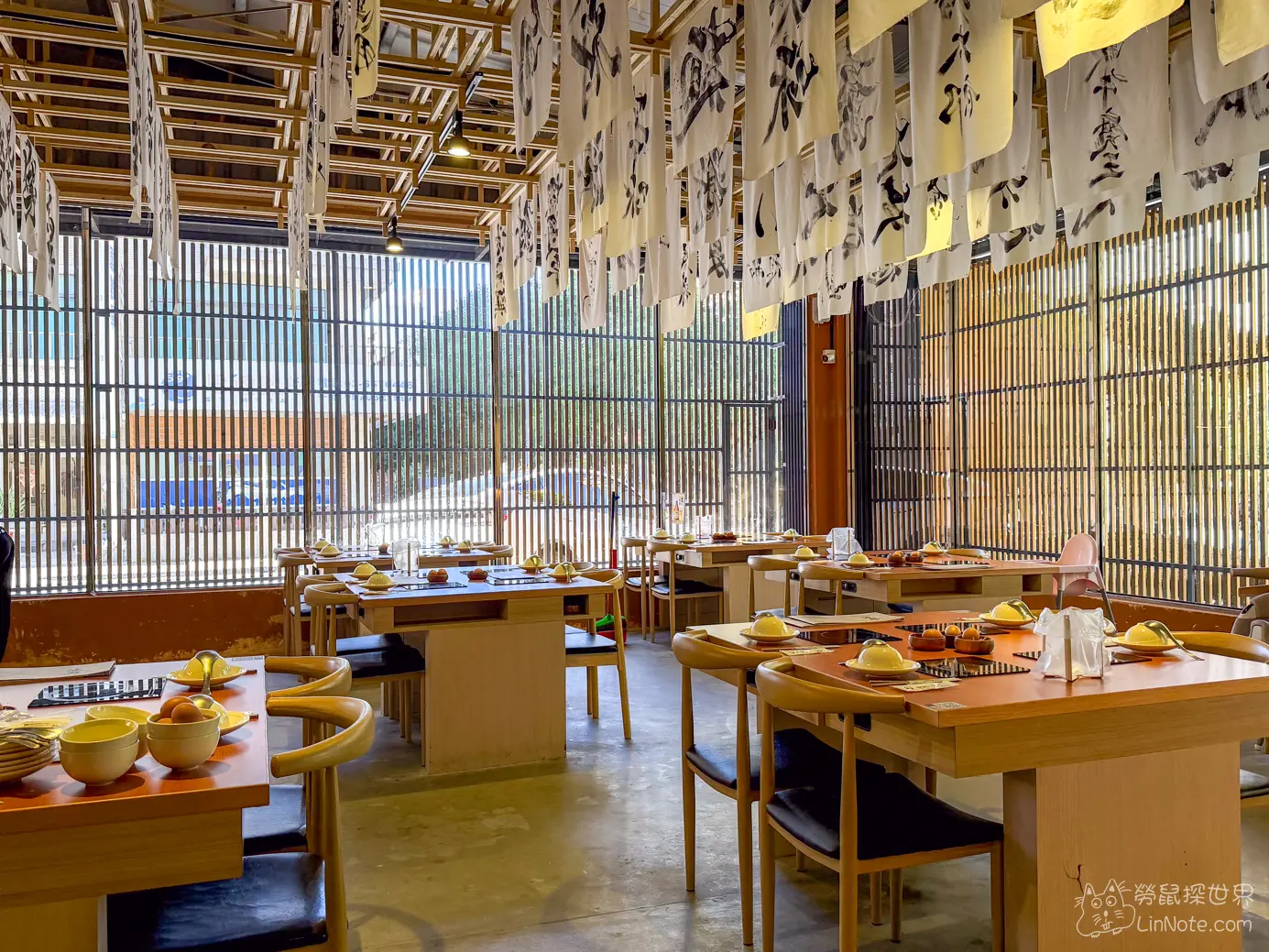 沐府火鍋店內擺設整齊的餐具與自然採光落地窗景