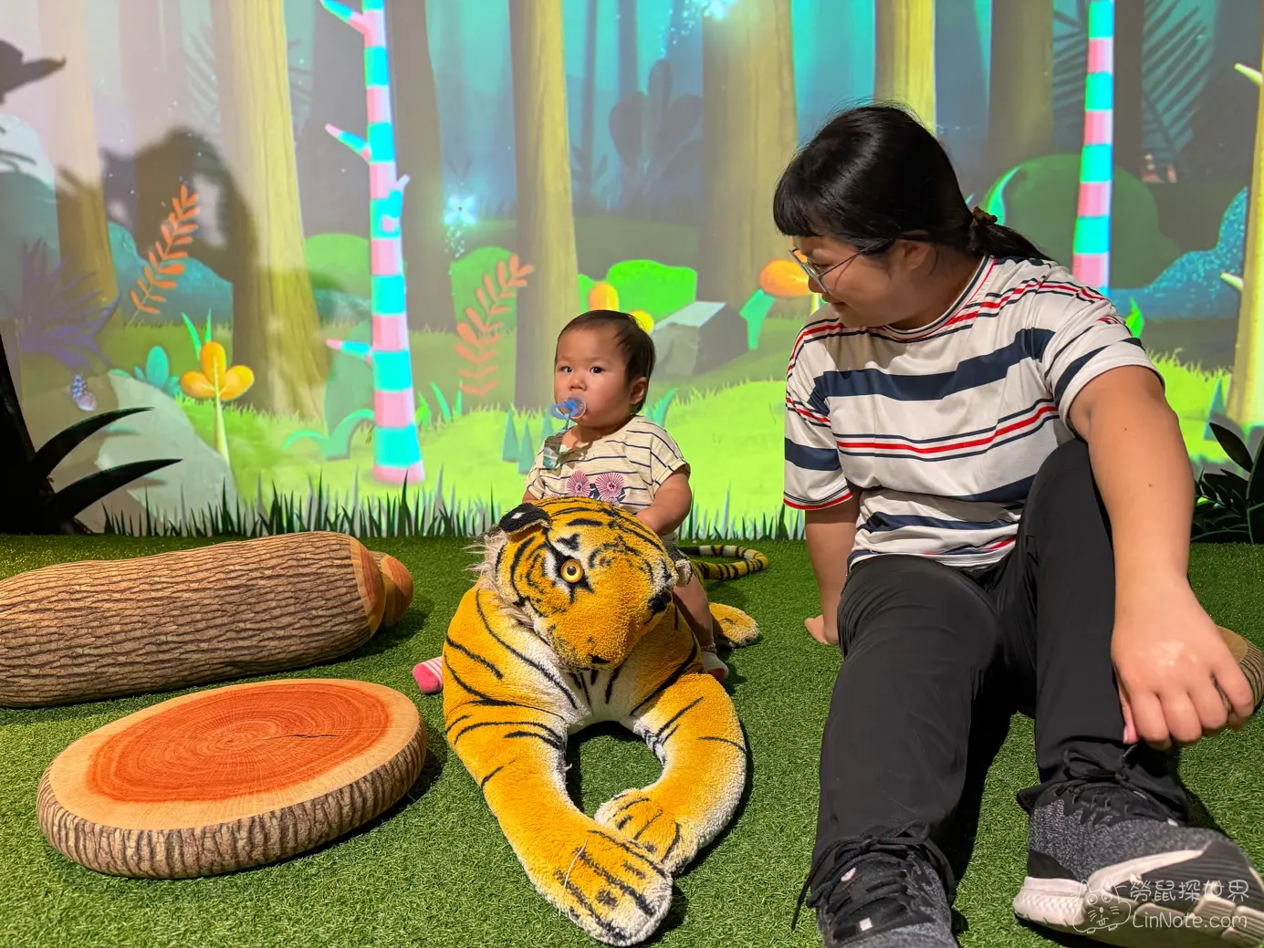 幼童騎在森林造景區的老虎玩偶背上開心拍照