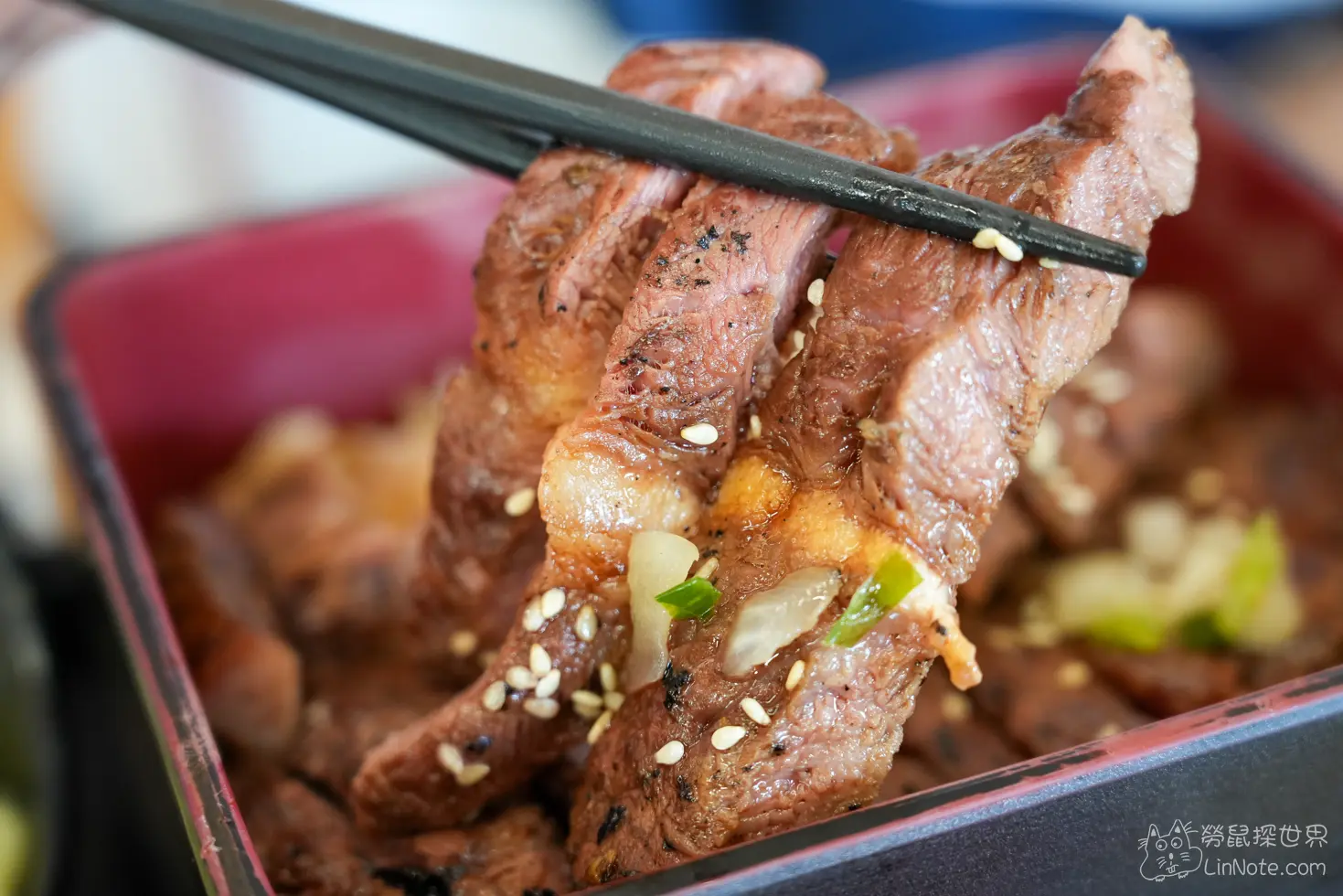 黑色筷子夾起厚切炙燒牛排肉片展現多汁切面