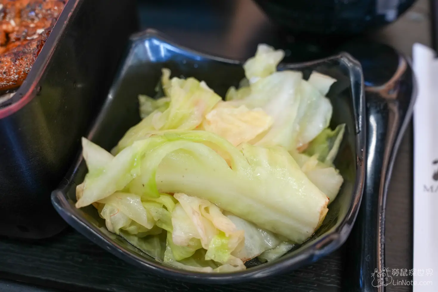 黑色小碗內盛裝的油亮清脆炒高麗菜特寫