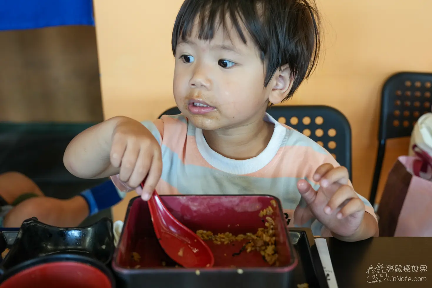 小朋友在餐廳座位上拿著湯匙享用定食餐點